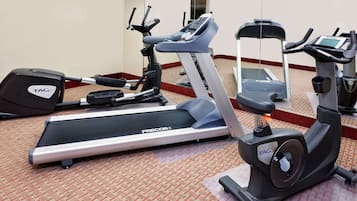 Un gimnasio de hotel con cintas de correr, elípticas y bicicletas estáticas.