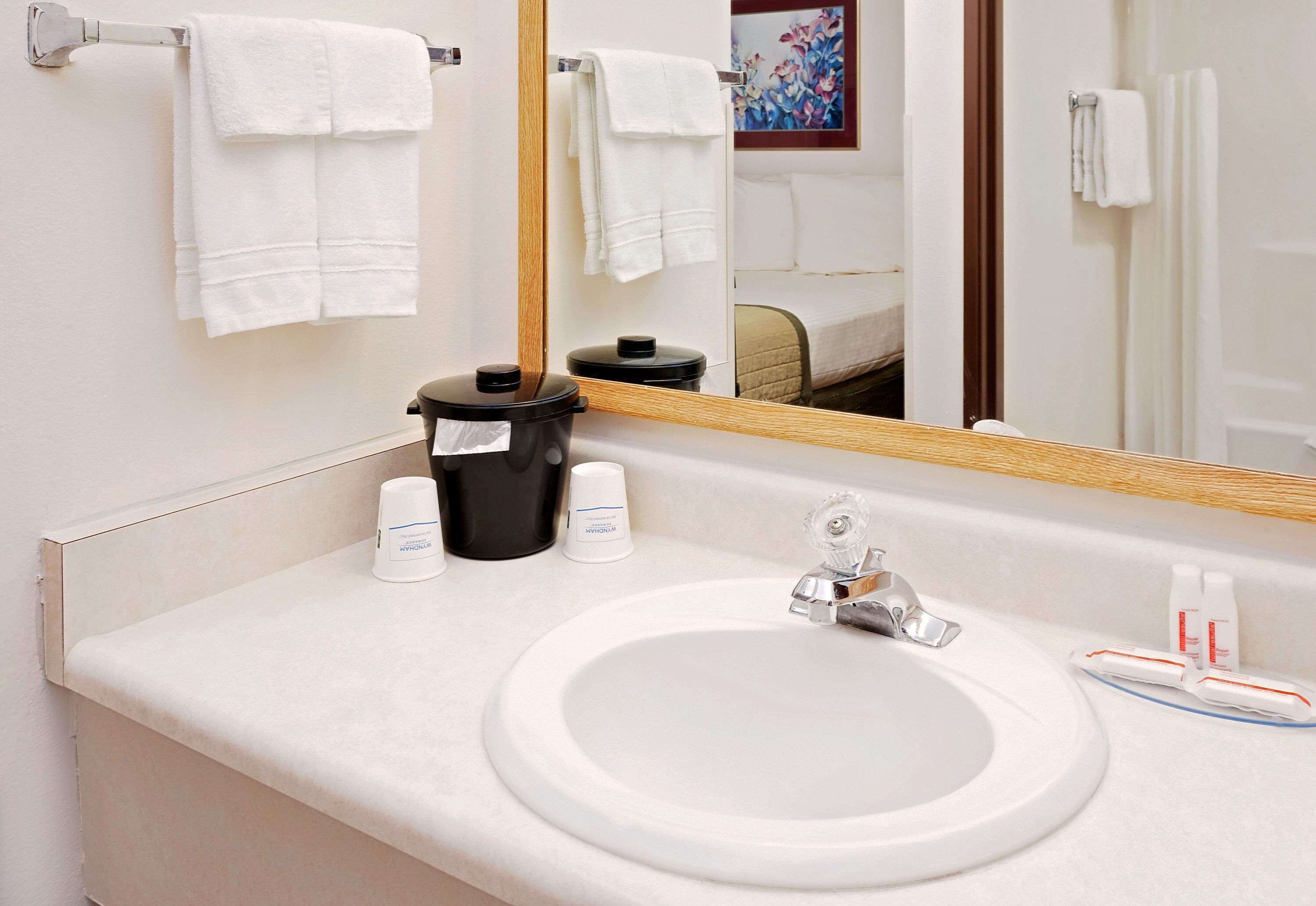 Un baño de hotel con un lavamanos blanco, un espejo y toallas colgadas en un tendedero.