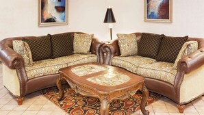 A corner sofa set with a matching coffee table, a patterned rug, and two abstract paintings on the walls. - Baymont by Wyndham St. Joseph/Stevensville (Stevensville)