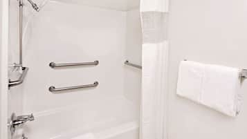 A bathroom with a bathtub, grab bars, a showerhead, and a towel rack.
