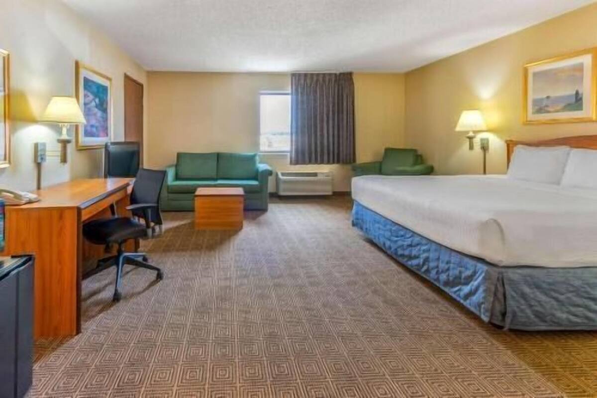 Ein Hotelzimmer mit Bett, Schreibtisch, Stuhl, Sofa und einem kleinen Tisch.