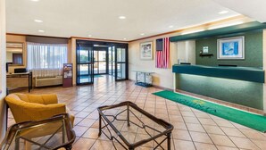 A lobby with a reception desk, American flag, and a green carpet with 'Quinta Suites' logo. - La Quinta Inn & Suites by Wyndham Las Cruces Organ Mountain (Las Cruces)