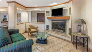 A living room with striped sofas, a glass coffee table, a fireplace, and a television. - La Quinta Inn & Suites by Wyndham Las Cruces Organ Mountain (Las Cruces)