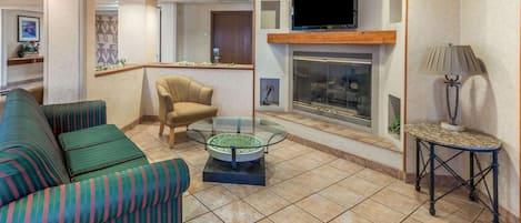 A living room with striped sofas, a glass coffee table, a fireplace, and a television.