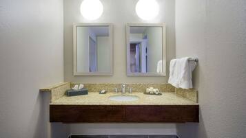 A bathroom with a double sink, two mirrors, and a towel rack.