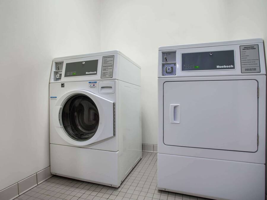 Deux machines à laver blanches et modernes, fixées au mur, dans une buanderie propre carrelée.