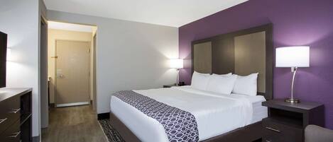Une chambre d’hôtel avec un grand lit, une table de chevet, un bureau et une chaise.