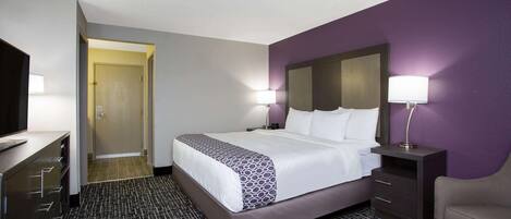 A hotel room with a bed, a desk, a chair, and a TV.