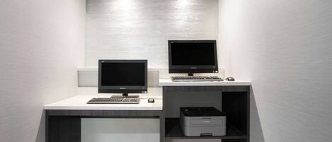 A compact office space with two monitors, a keyboard, and a printer on a white desk against a textured wall.
