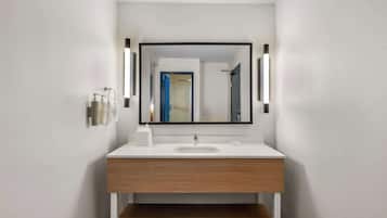 A modern bathroom with a white sink, wooden vanity, and a large mirror.
