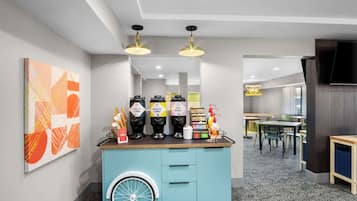 A modern coffee station with a blue counter, a wheelchair-accessible ramp, and a seating area with tables and chairs.