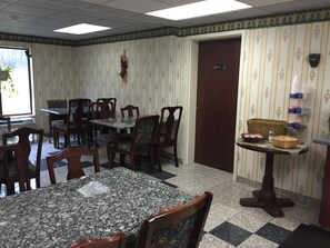 A dining area with a marble table and wooden chairs, a small side table with baskets, and a door marked "Employees Only".