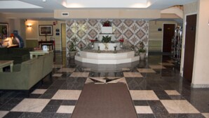 A lobby with a checkered floor, a reception desk, and a decorative wall with patterned tiles. - Aderi Hotel Niantic (Niantic)