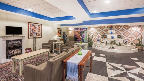 A hotel lobby with a fireplace, sofas, a TV, and a decorative wall. - Aderi Hotel Niantic (Niantic)
