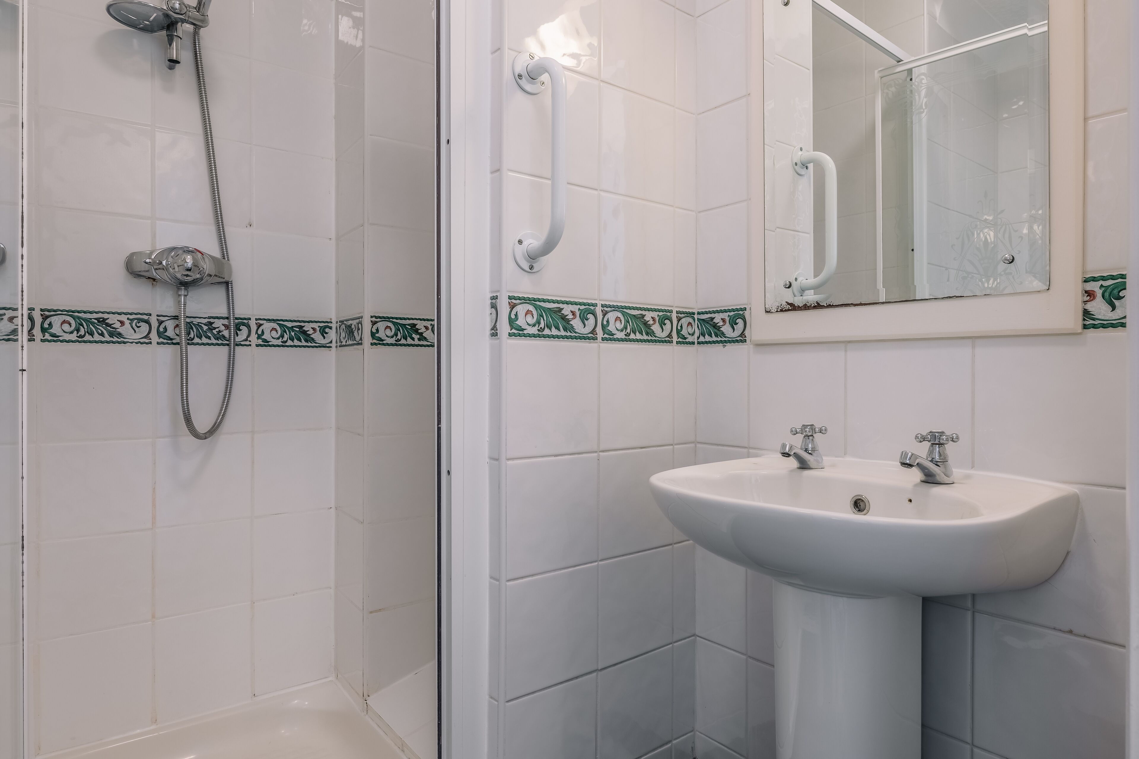 A bathroom with a shower, a sink, and a mirror.