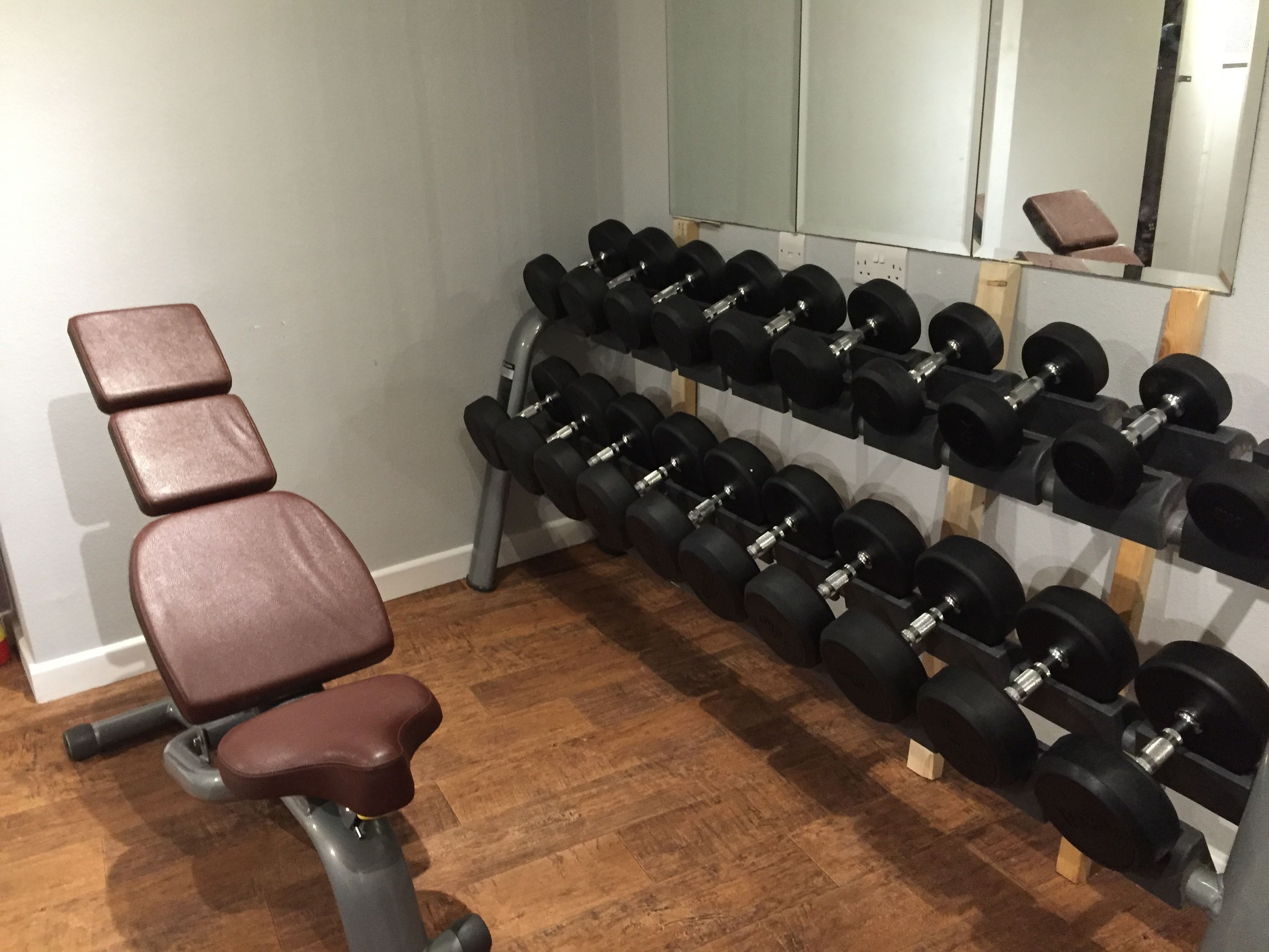 A gym with a bench and a rack of dumbbells.