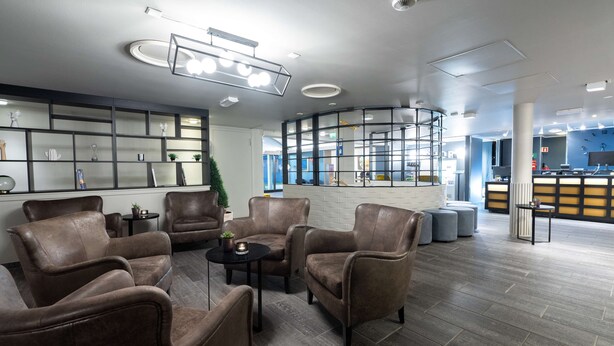 A modern lobby with leather armchairs, a coffee table, and a reception desk. - Scandic Vadsø (Vadsø)