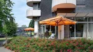 A building with outdoor seating and a flower bed. - Ringhotel Parkhotel Witten (Witten)