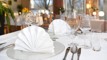 A dining table set with white napkins, clear glassware, and silverware.