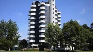 A high-rise building with multiple balconies, surrounded by trees and a clear sky. - Ringhotel Parkhotel Witten (Witten)