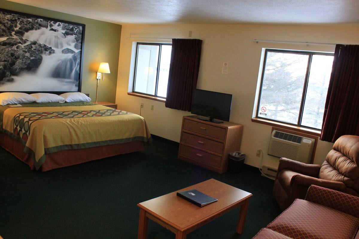 Een hotelkamer met een bed, een televisie, een bureau, een stoel en een raam.