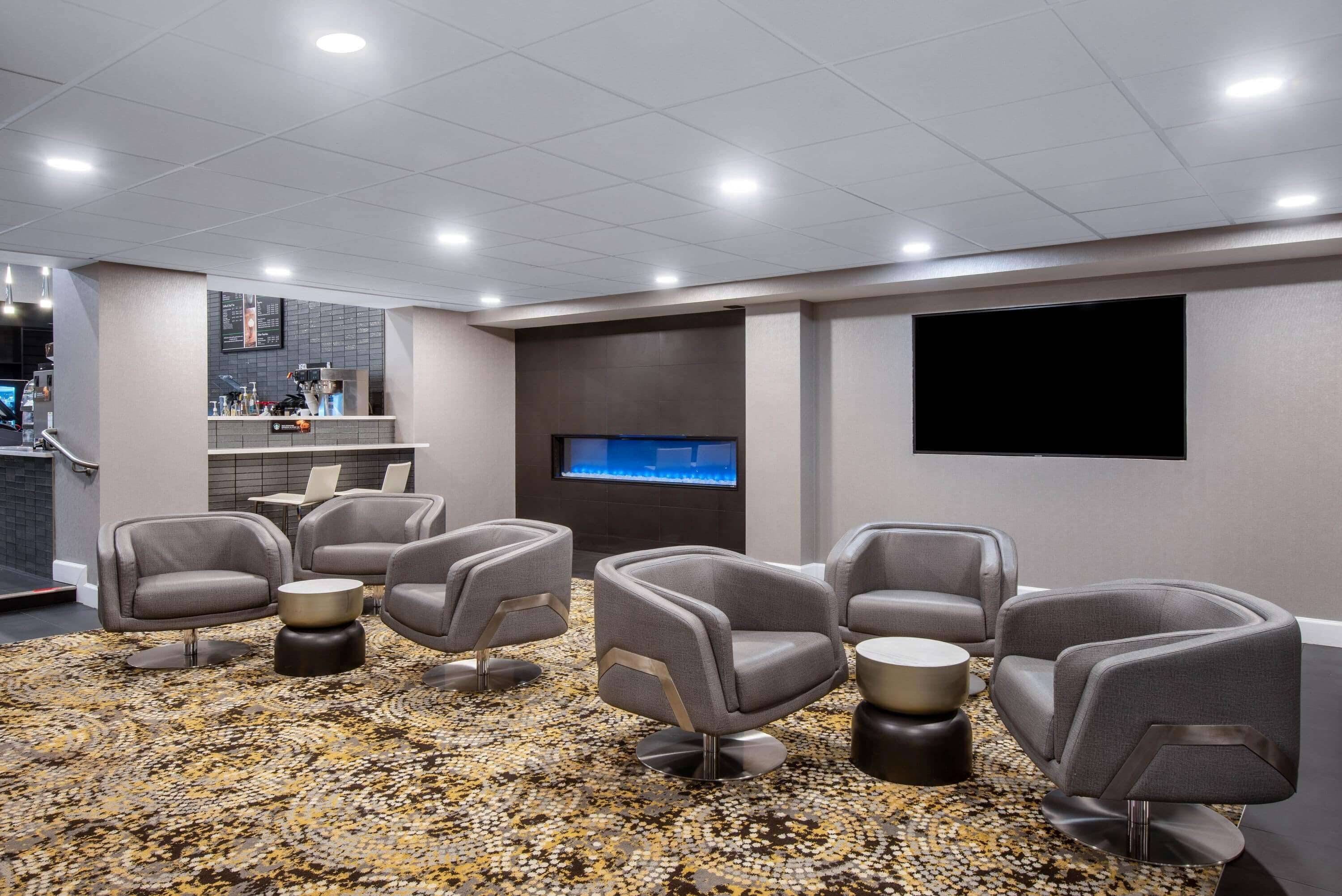 A modern lounge area with comfortable seating, a flat-screen TV, and a bar area.