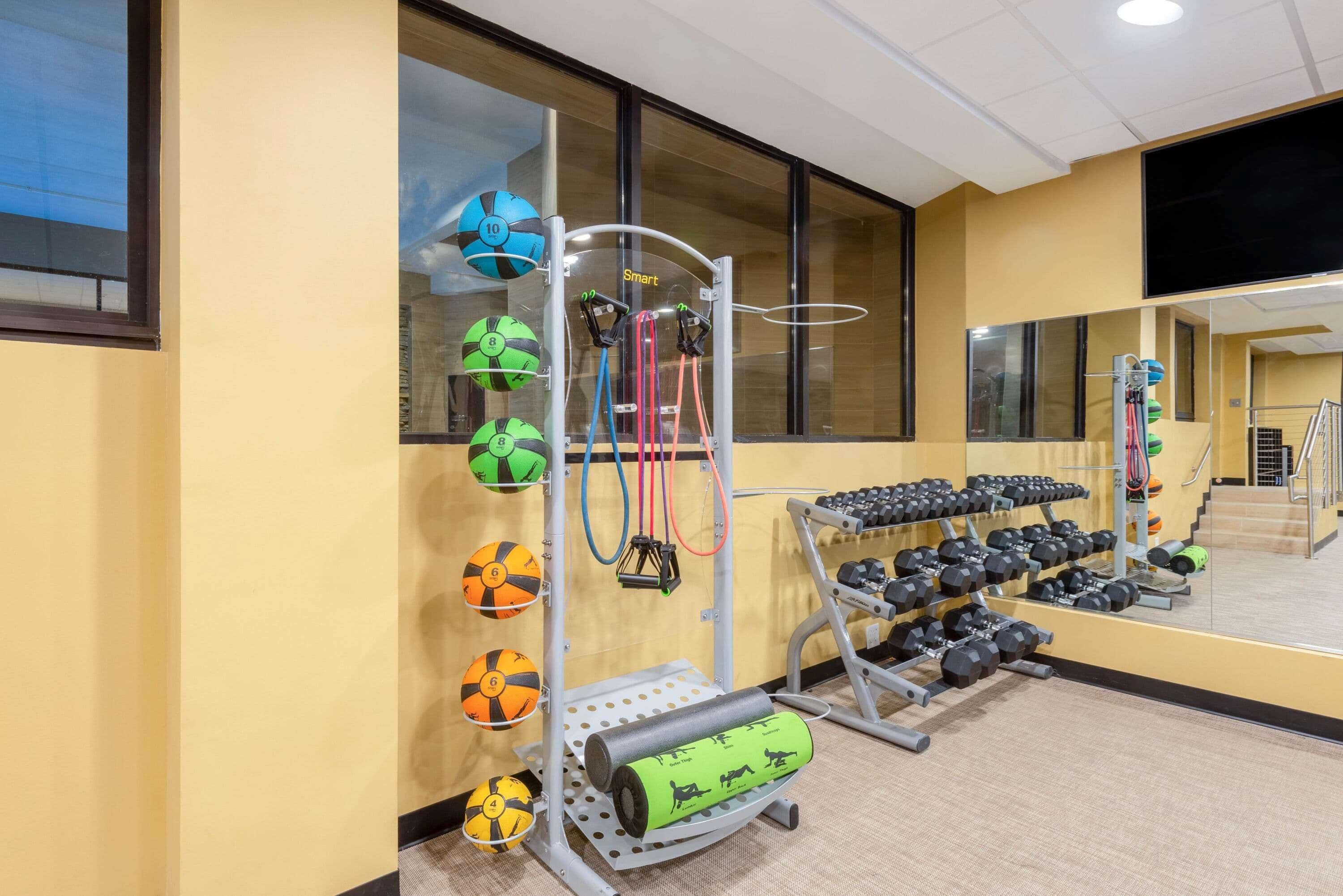 A gym with exercise equipment, a mirror, and a window.