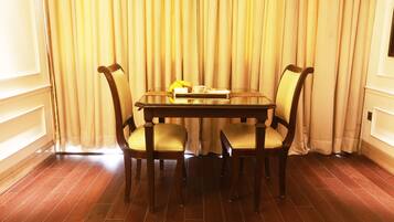 Un coin repas avec une table en bois et quatre chaises, un panier de fruits et un petit livre posé sur la table.