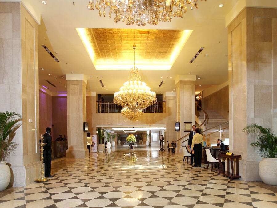 A spacious lobby with a large chandelier, checkered floor, and marble walls.