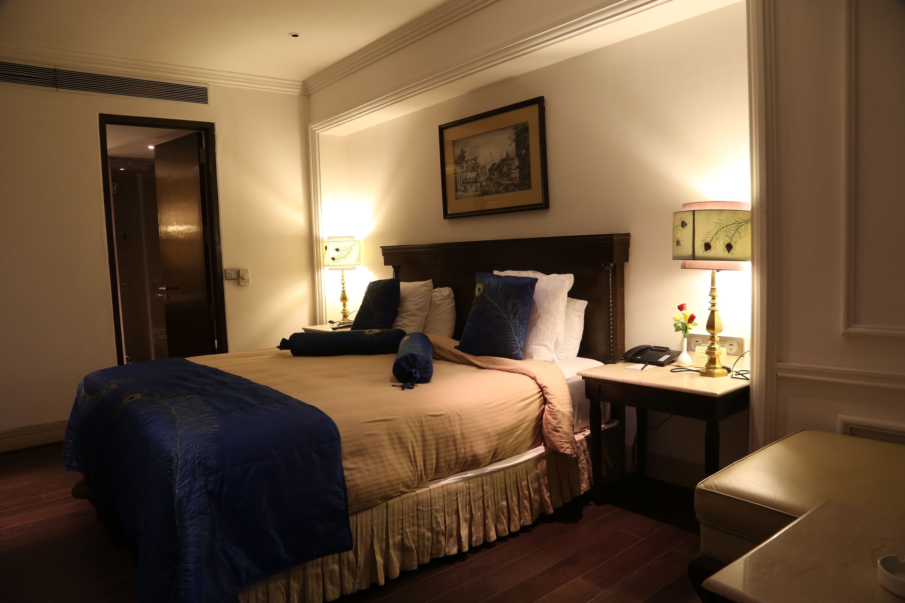 A hotel room with a large bed, bedside tables, a desk, and a chair.