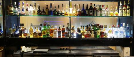 Un bar con varias estanterías llenas de botellas de licor y un refrigerador exhibidor.