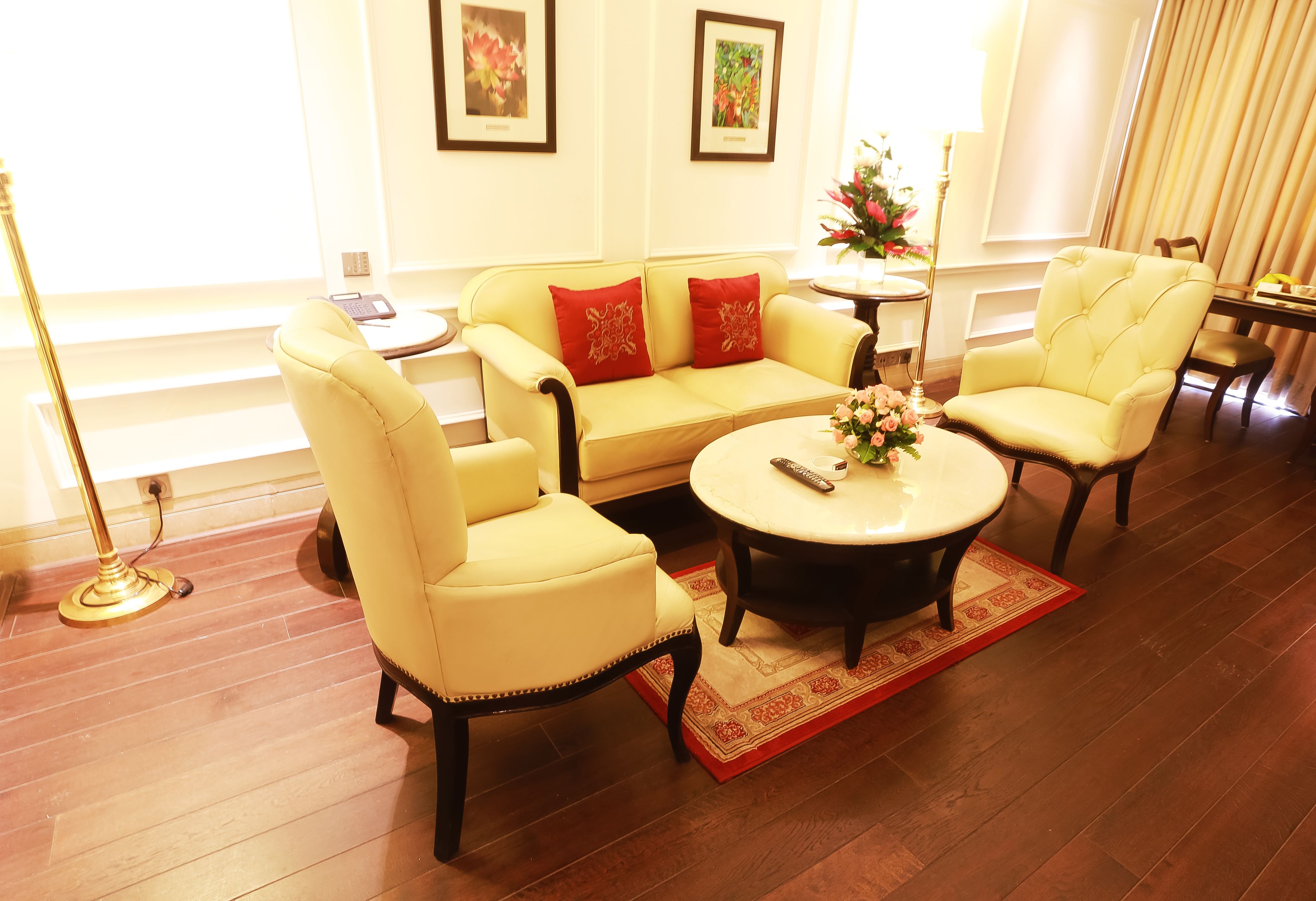 A well-lit living room with a sofa, two armchairs, a coffee table, and a small side table.