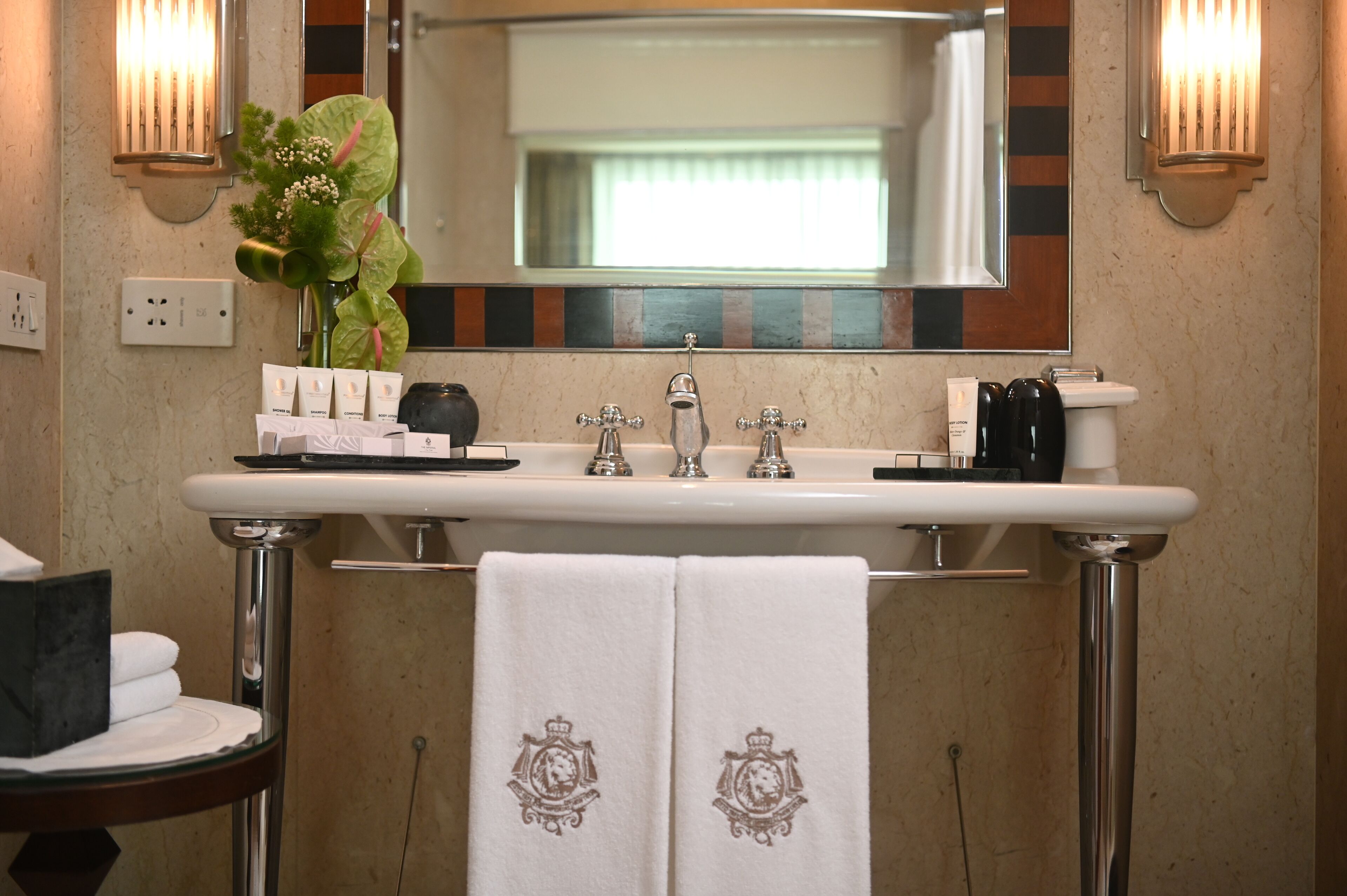 A bathroom with a white sink, two faucets, a mirror, and a towel rack with two towels.