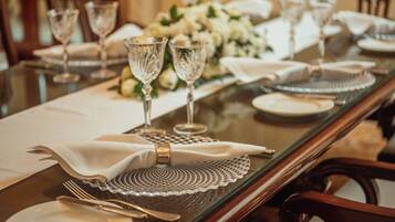 A dining table set with crystal glassware, white napkins, and a centerpiece of white flowers.