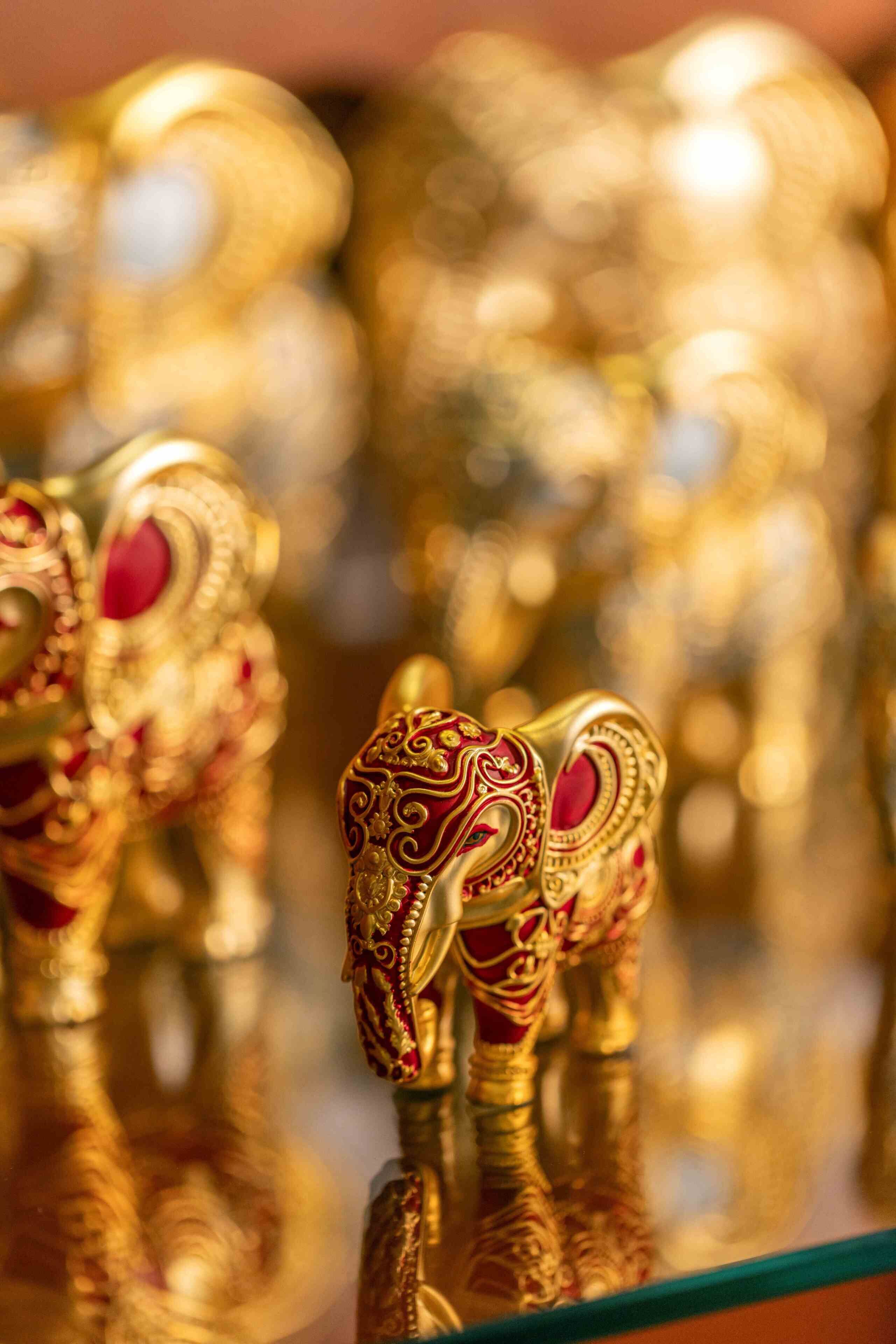 Nahaufnahme kunstvoll gestalteter, goldener Elefantenstatuen mit roten Akzenten.