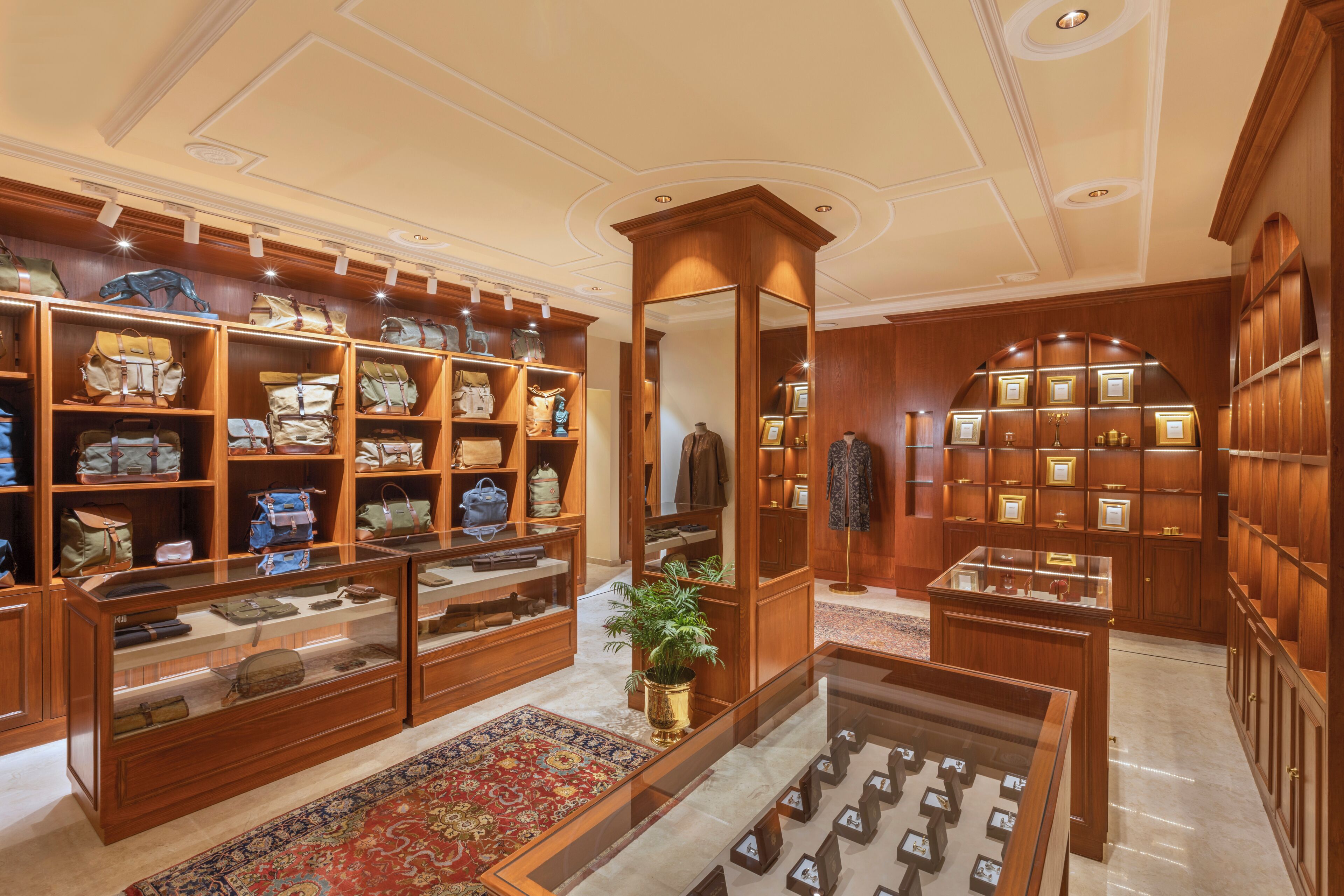 A luxury boutique with wooden display cases, a central mirror, and a patterned carpet.