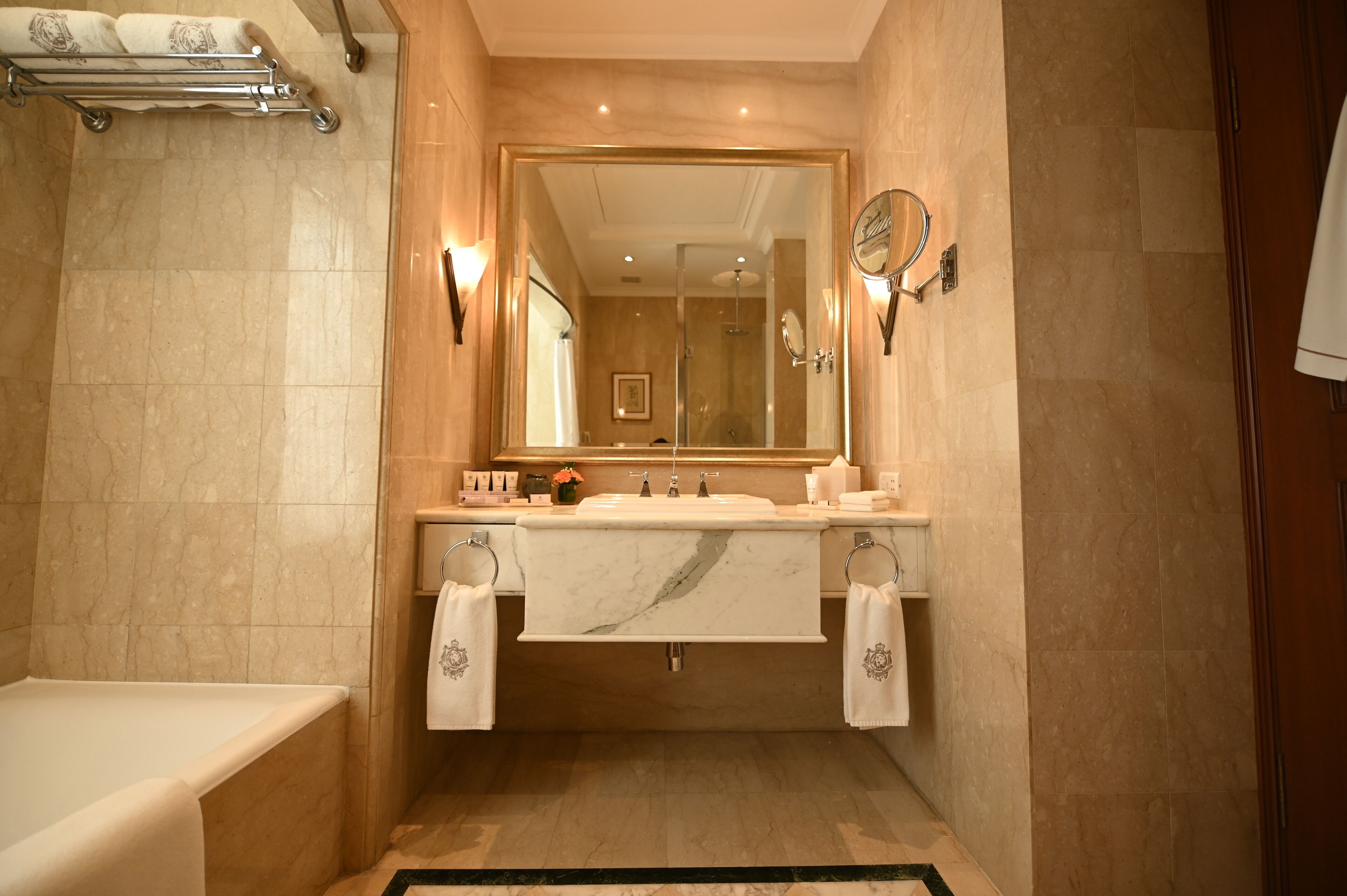 Un baño con un espejo grande, dos lavamanos, una bañera y un perchero para toallas.