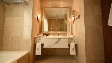 Un baño con un espejo grande, dos lavamanos, una bañera y un perchero para toallas.