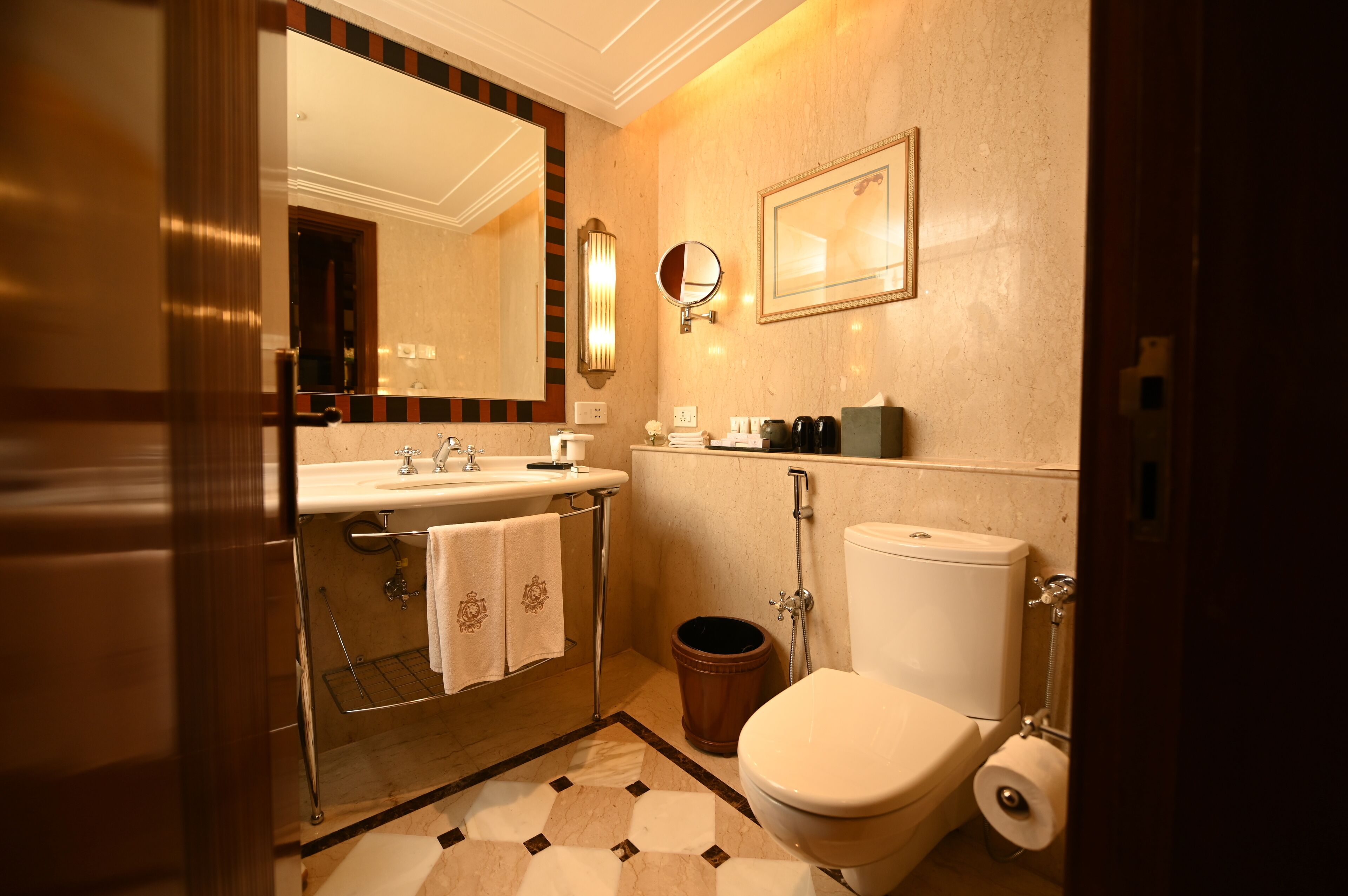 Une salle de bain équipée d’un lavabo, d’un miroir, de toilettes et d’une poubelle.