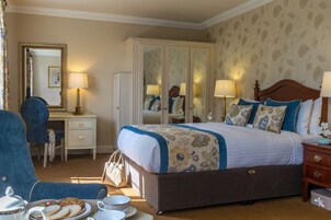 Habitación de hotel ordenada con una cama grande, un escritorio, una silla y un armario.