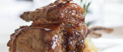 A plated dish with a meat centerpiece, a sauce, and some berries.