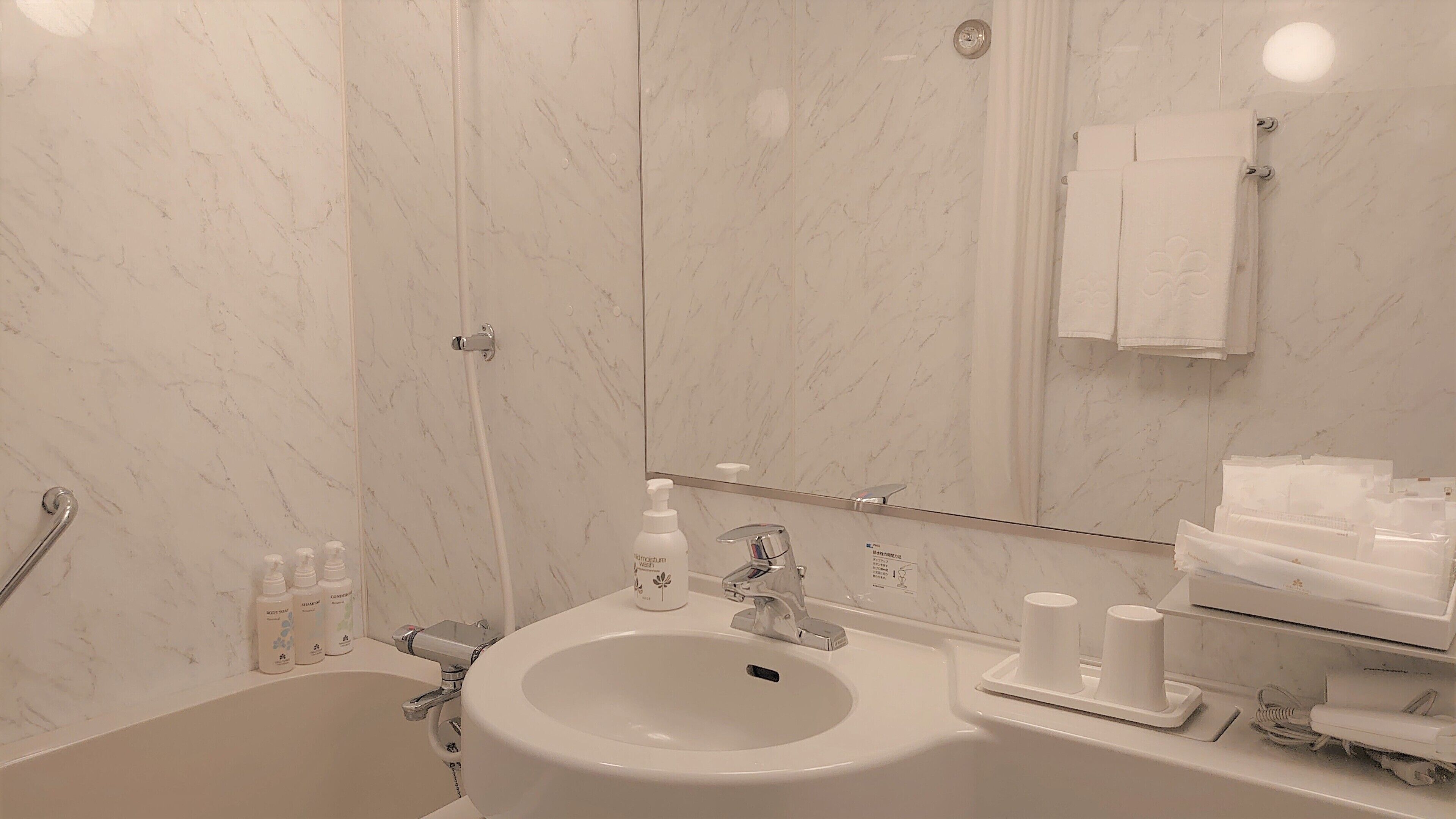 A bathroom with a sink, mirror, and toiletries.