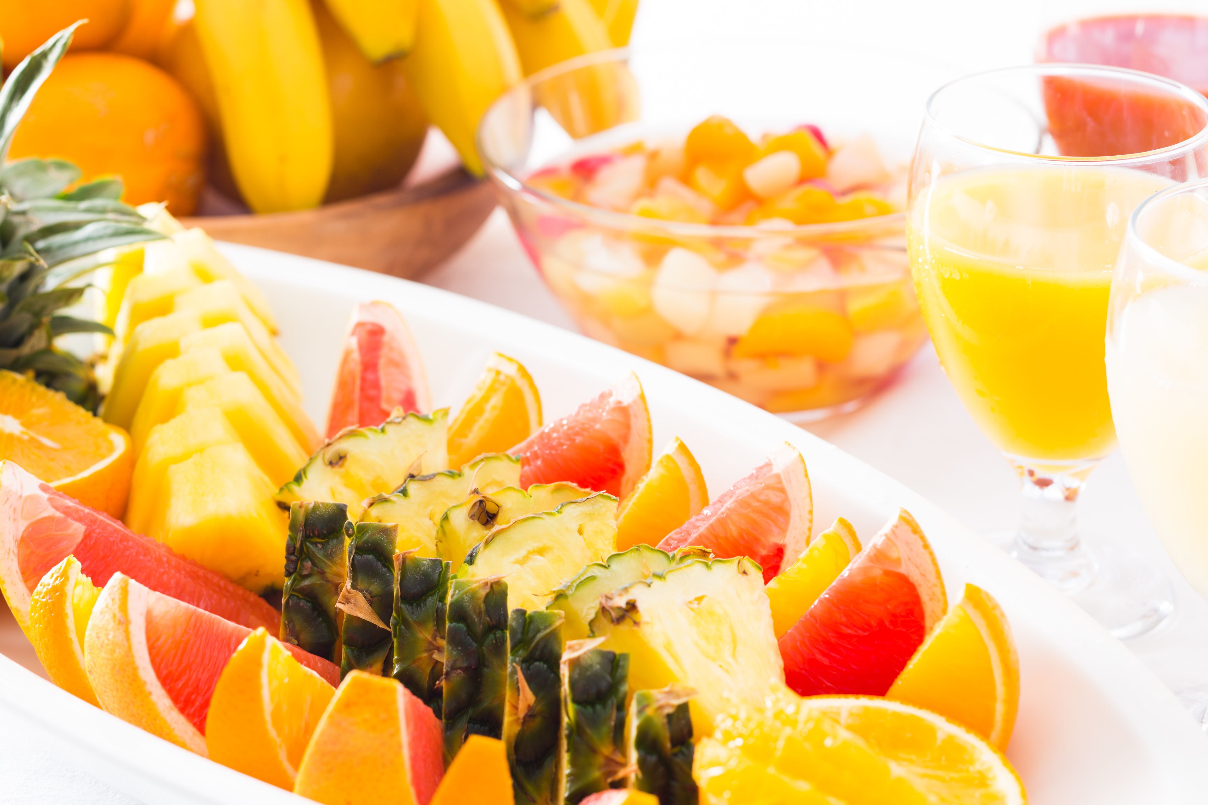 A fruit platter with pineapple, mango, and oranges.