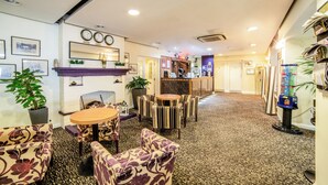 Un hall d’hôtel doté d’une cheminée, d’un espace salon et d’un bar.
