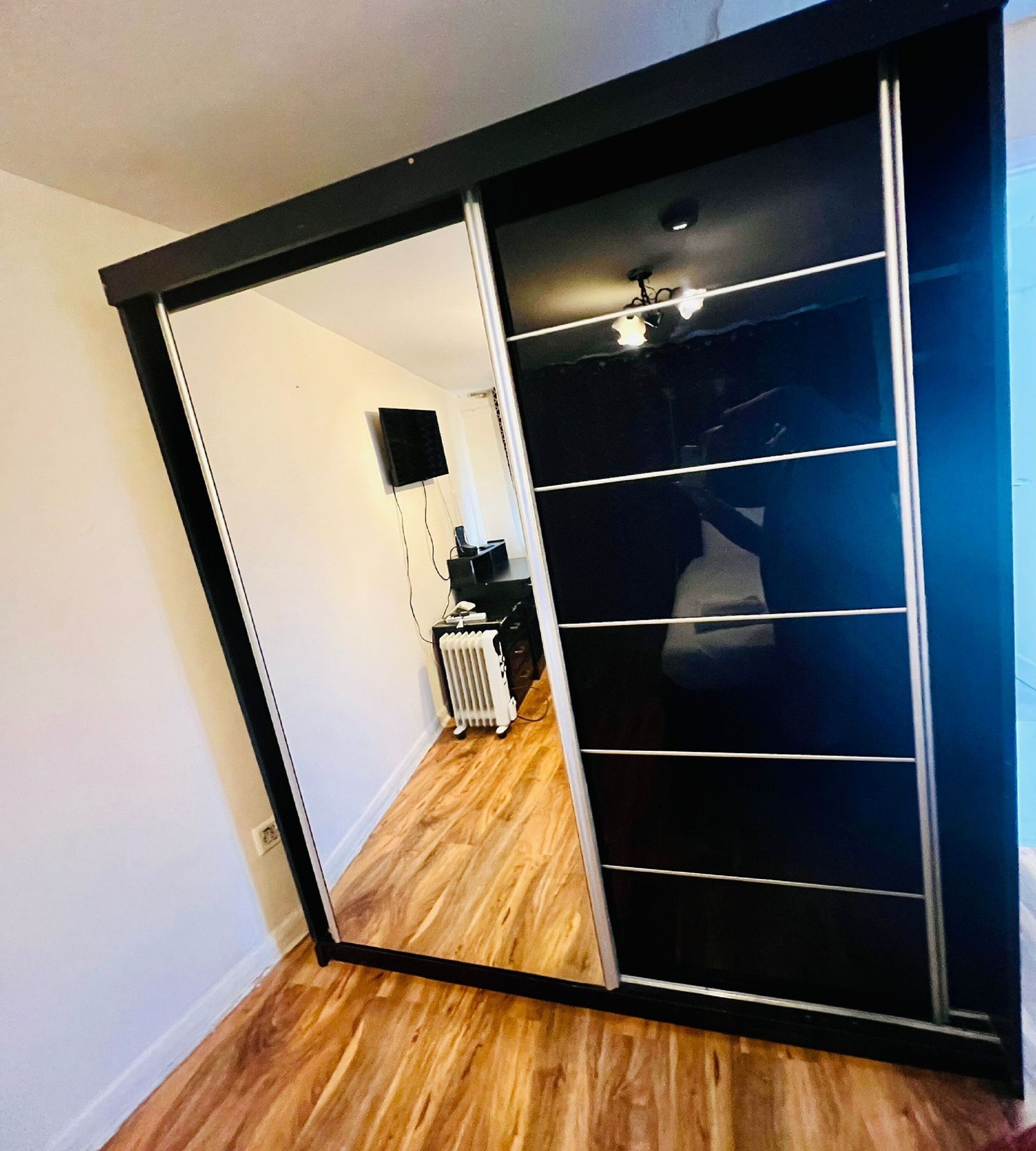 A room with a sliding door leading to a dark room with a ceiling fan.