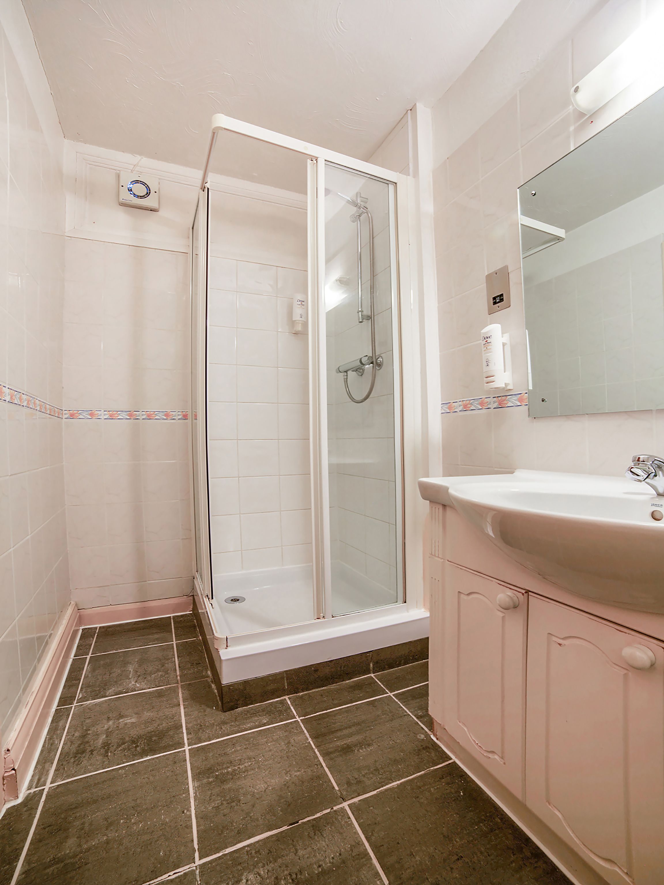 Un baño con ducha de vidrio, lavamanos con espejo y paredes de azulejos.