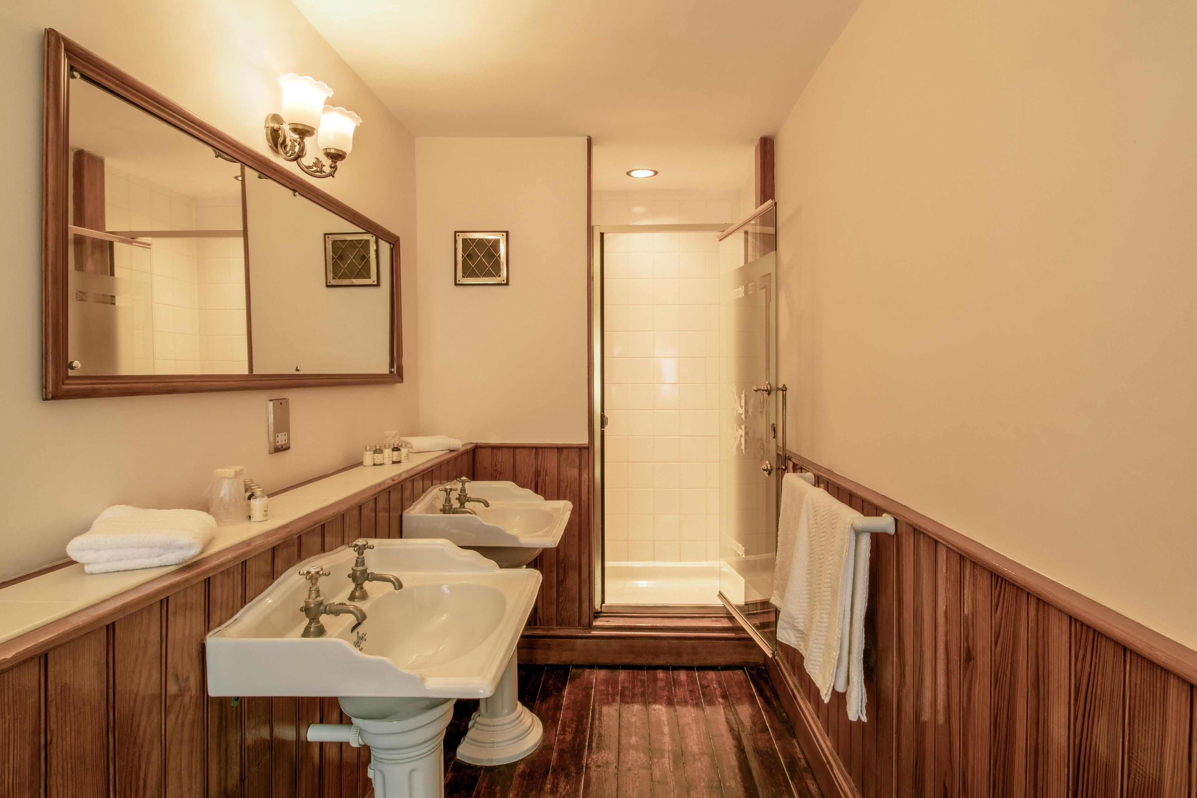 A bathroom with three sinks, a large mirror, and a shower area.