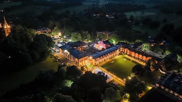 Stunning historic building complex with multiple wings and a central courtyard, surrounded by beautifully maintained lawns and trees.