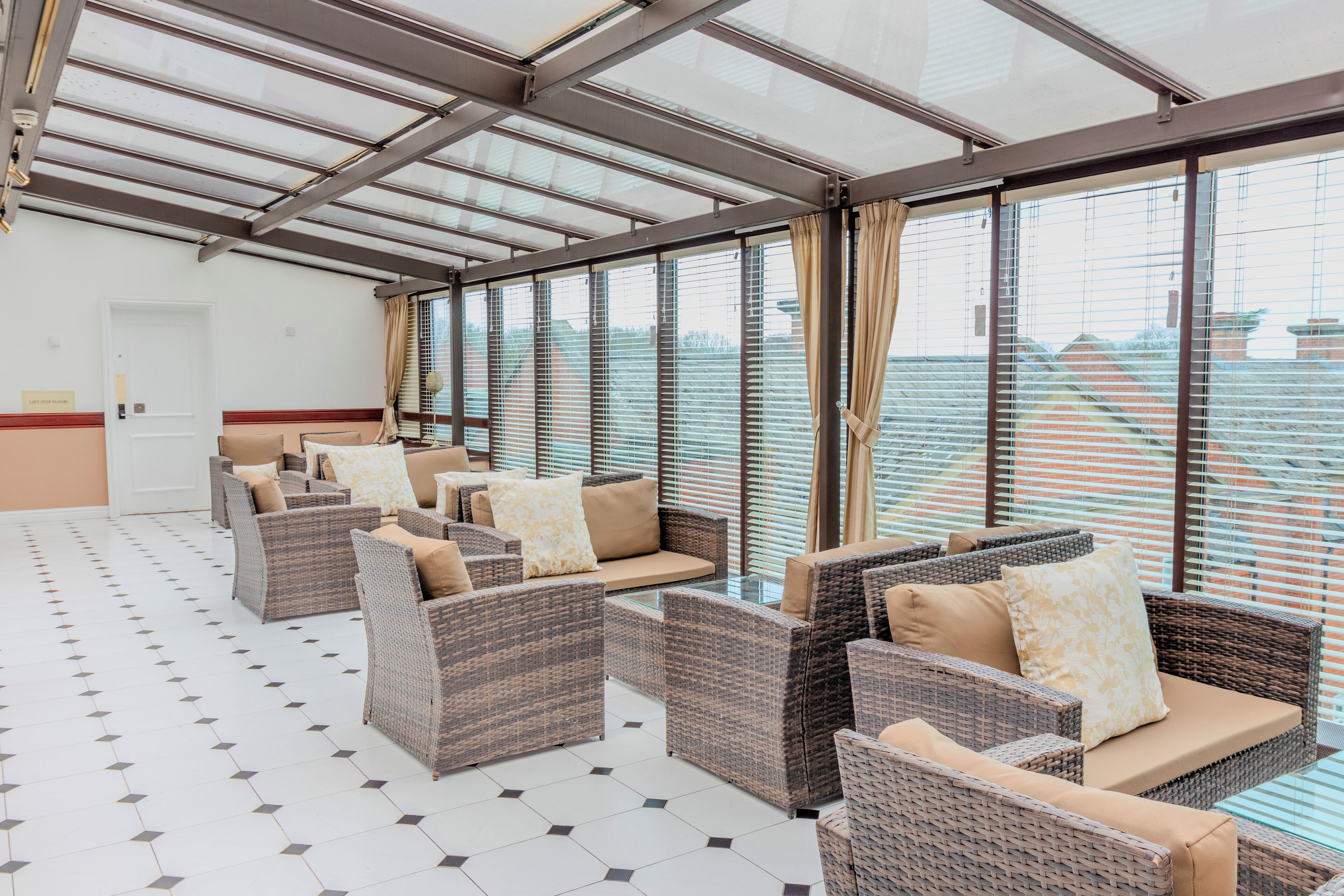 A spacious indoor seating area with wicker furniture and large windows.