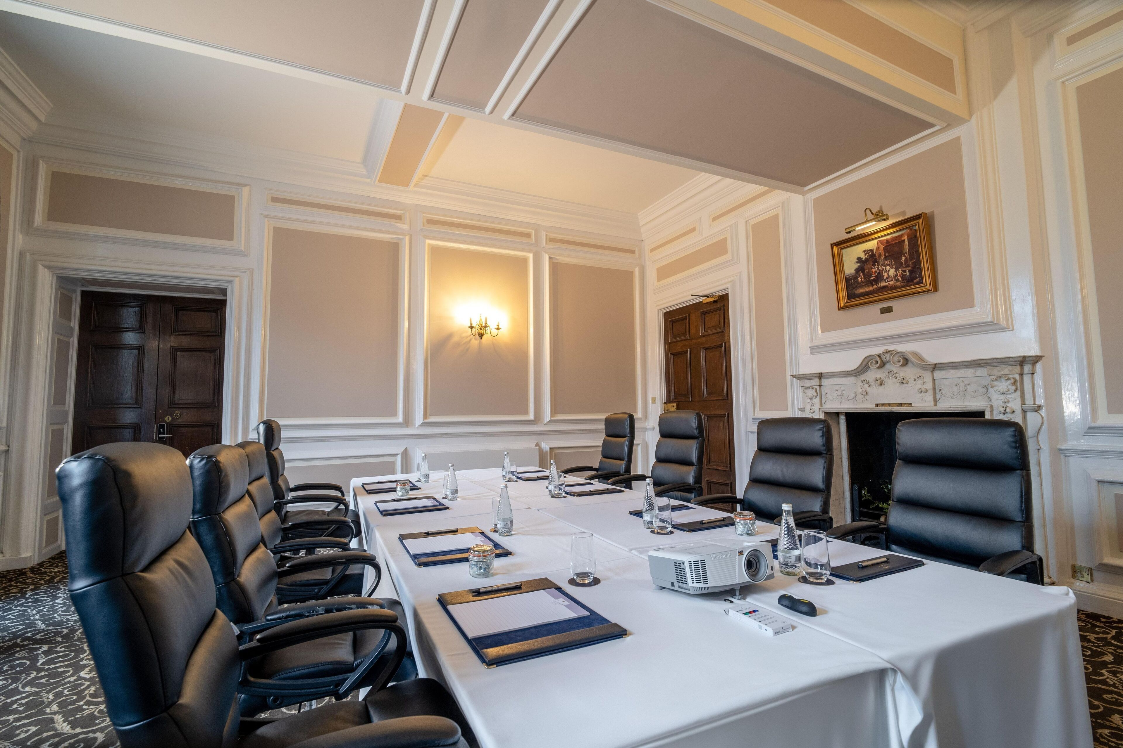A conference room with a long table, black leather chairs, a white tablecloth, and a fireplace.